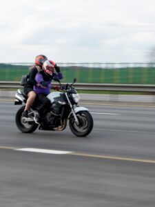 Deux personnes conduisent une moto sur une autoroute.