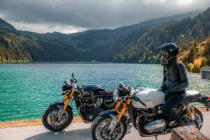 moto noire et orange près d'un plan d'eau pendant la journée
